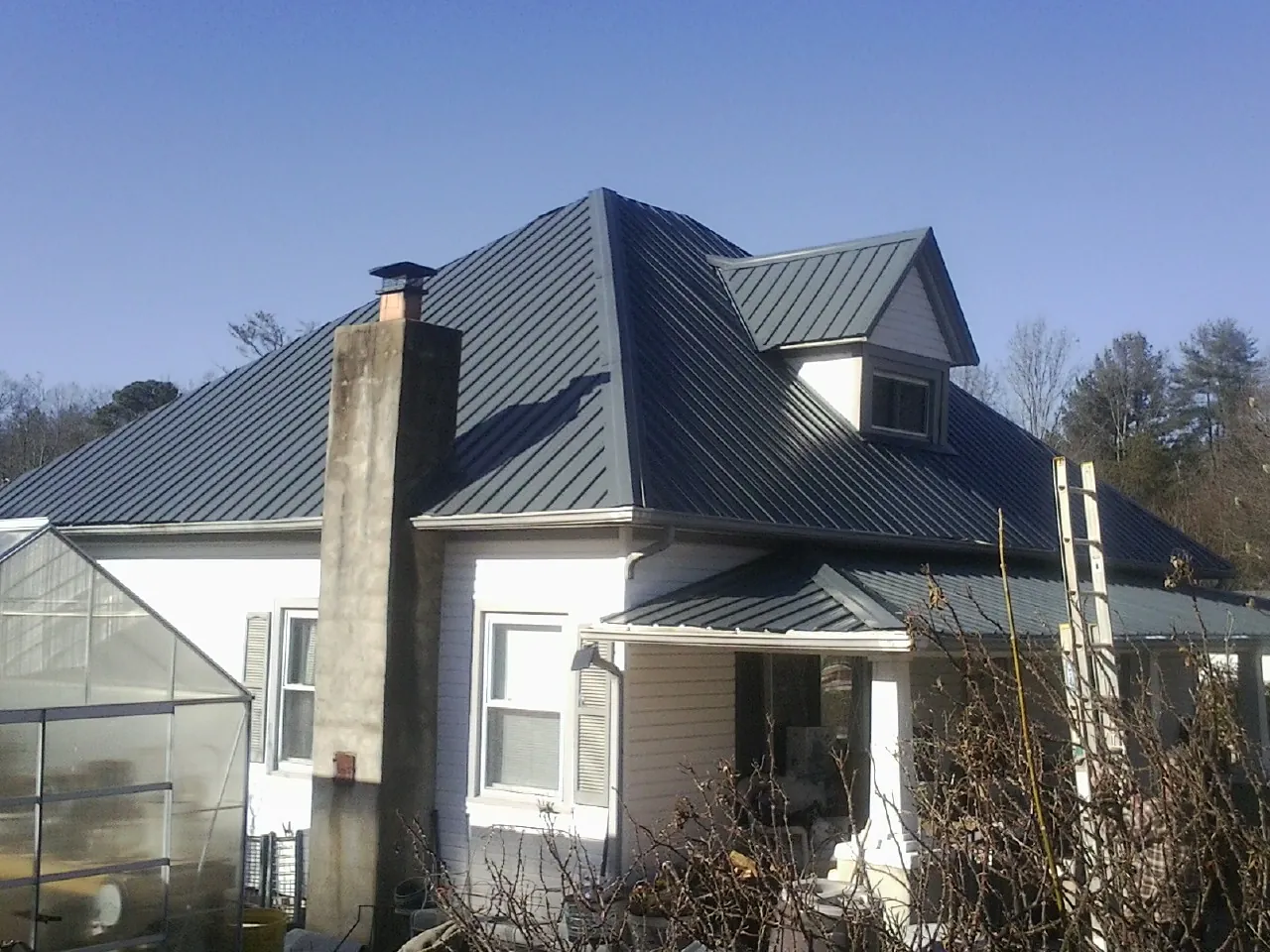 Dark blue standing seam metal roof on a white farmhouse with dormer — Slate & Tile Roof Repair by Roofing Brothers in South Fallsburg