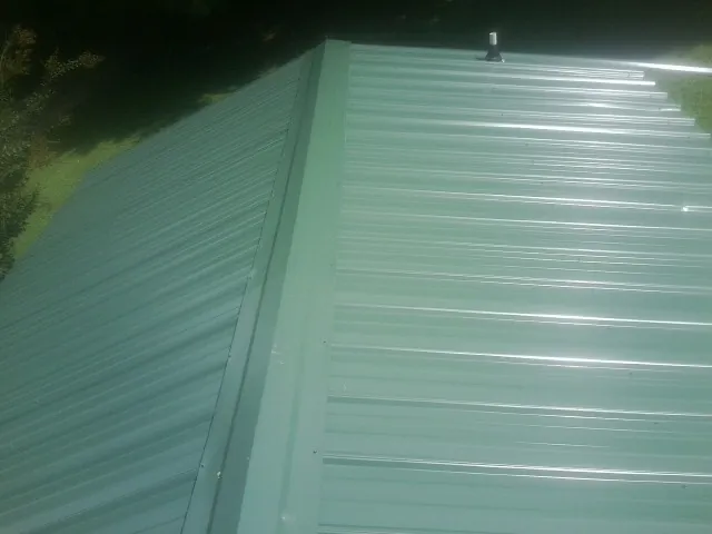 New green metal panels meeting at the ridge of a roof — Flat Roof Repair work by our crew in South Fallsburg