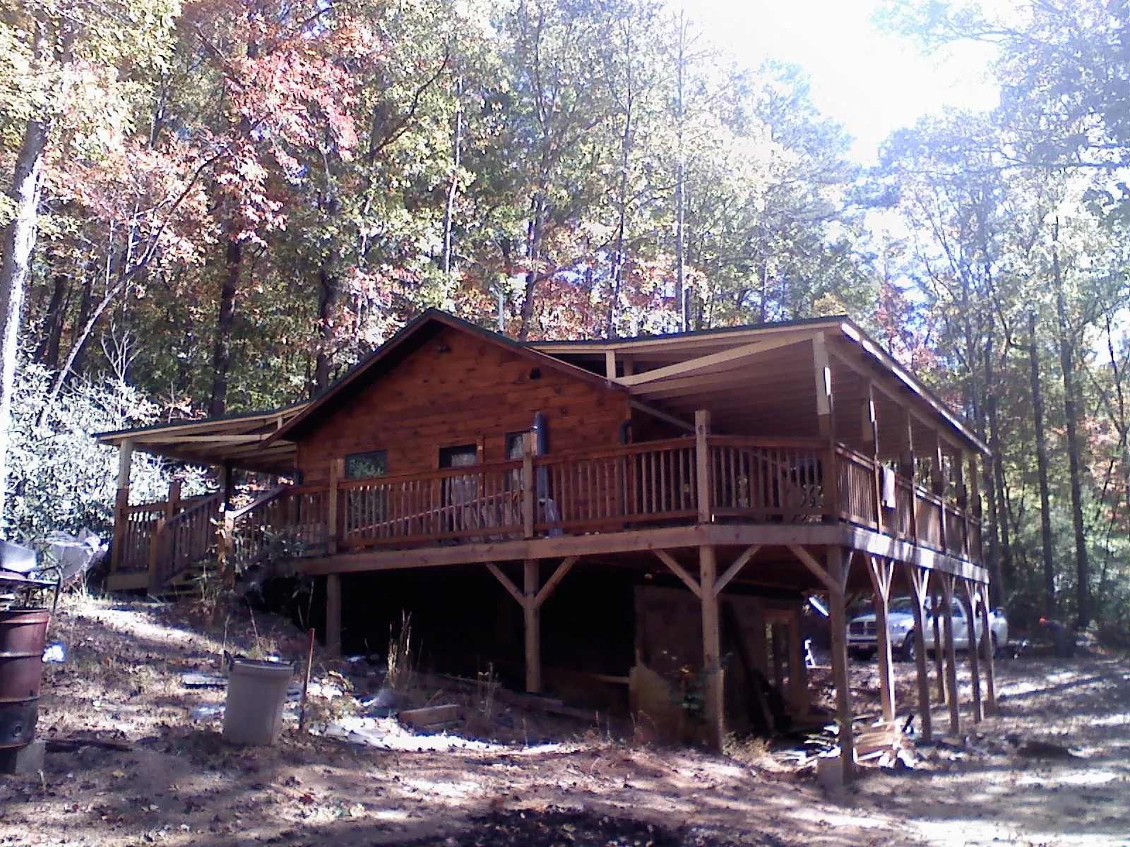 Log cabin with a wraparound porch and metal roof in the fall in South Fallsburg