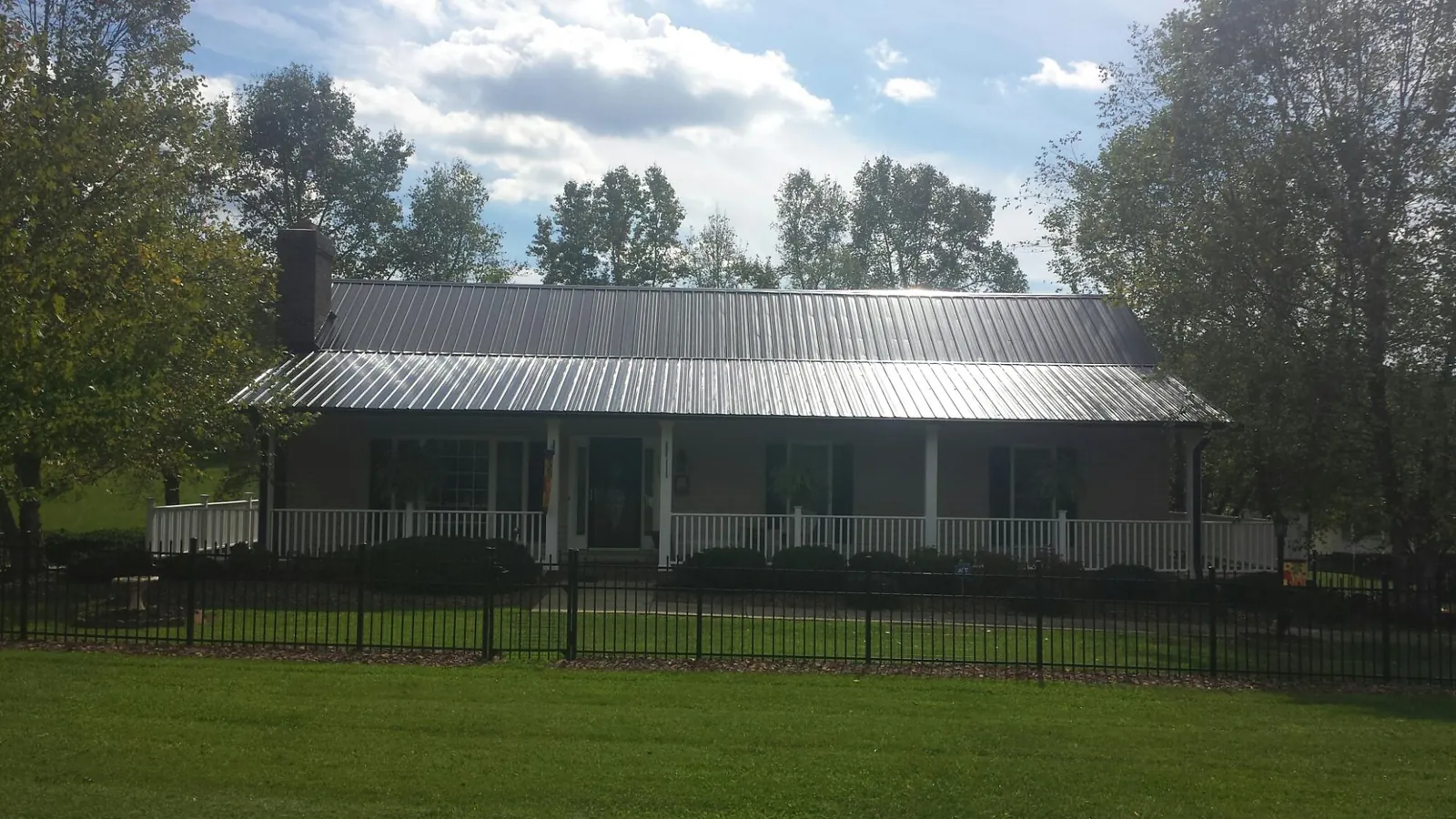 Gray metal roof on a brick ranch with a full width front porch — Gutter Guard Installation work by our crew in South Fallsburg