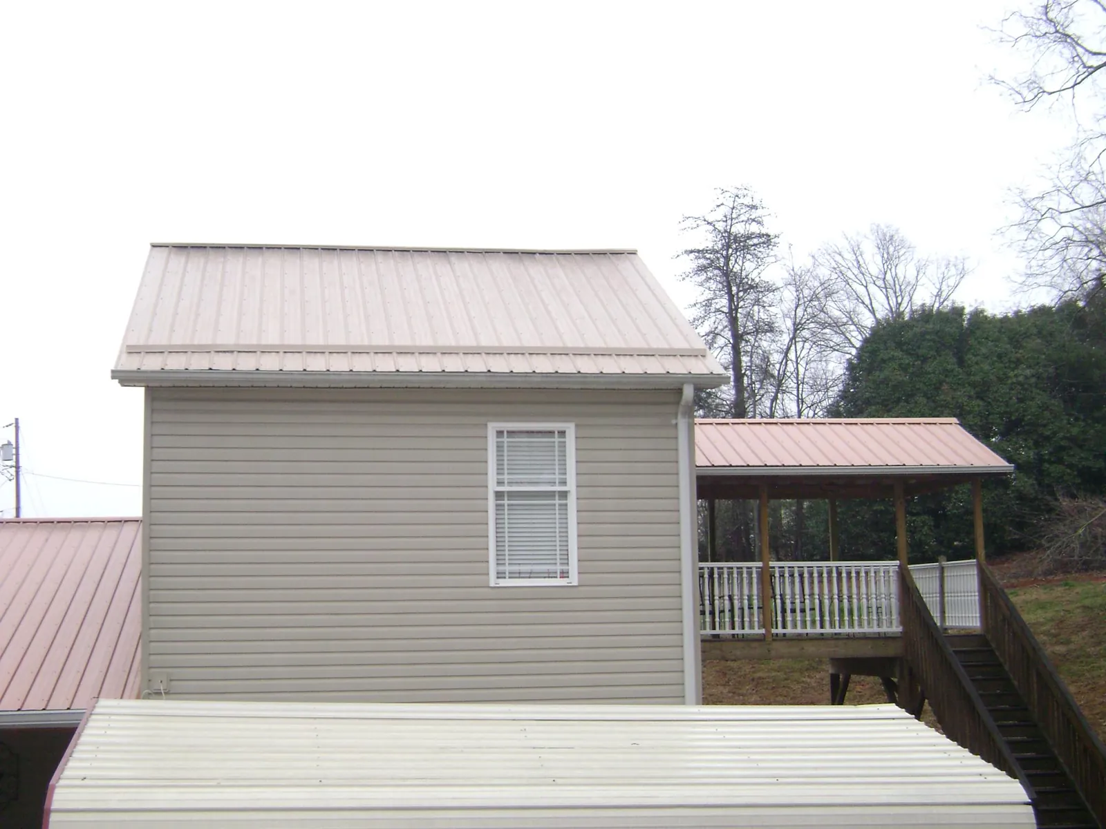 Tan metal roofs on a two story addition and attached porch, from a Roof Replacement job in South Fallsburg